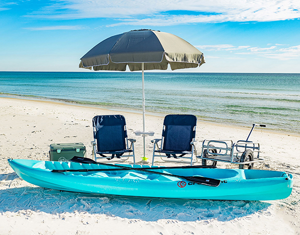 Beach umbrella, paddle board, and water-side gear prepared clearly on a sunny shoreline